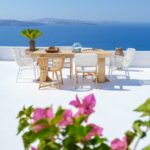 outside terrace of a restaurant by the ocean of Santorini Greece, chairs and tabel with flowers by