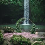 Round bronze wedding arch decorated with pink roses and greens. Unusual location for ceremony