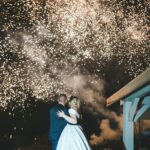 Vertical shot of a beautiful wedding couple on the firework background